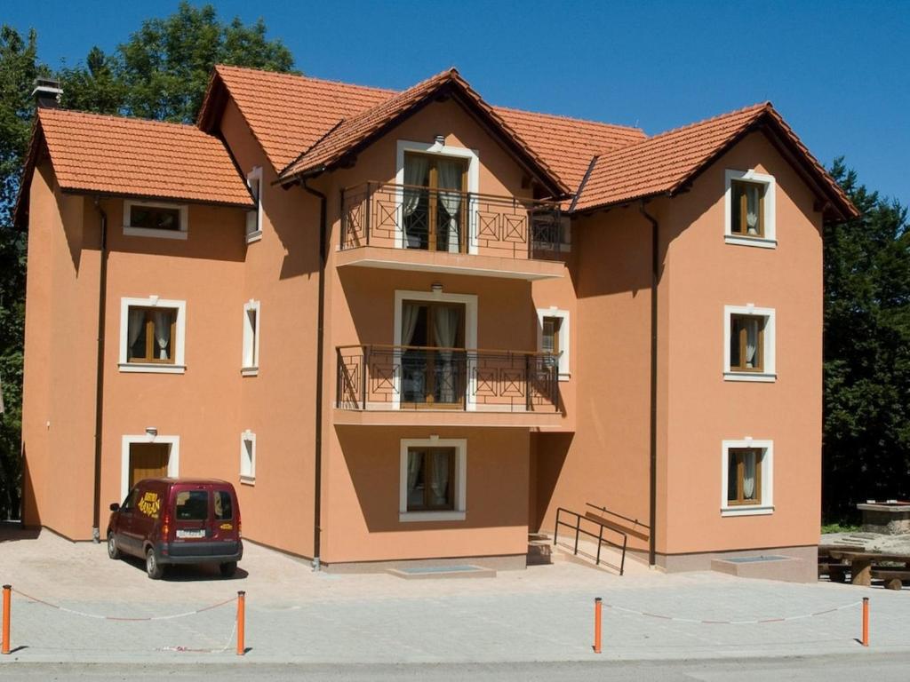 a house with a car parked in front of it at Apartments Manjan in Krasno Polje