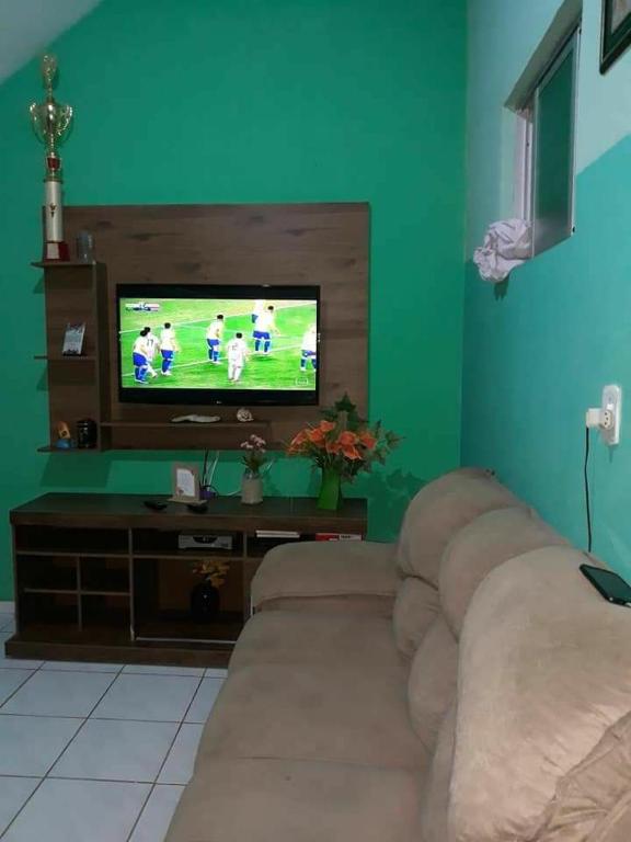 a living room with a couch in front of a television at Cantinho da bel in Maragogi