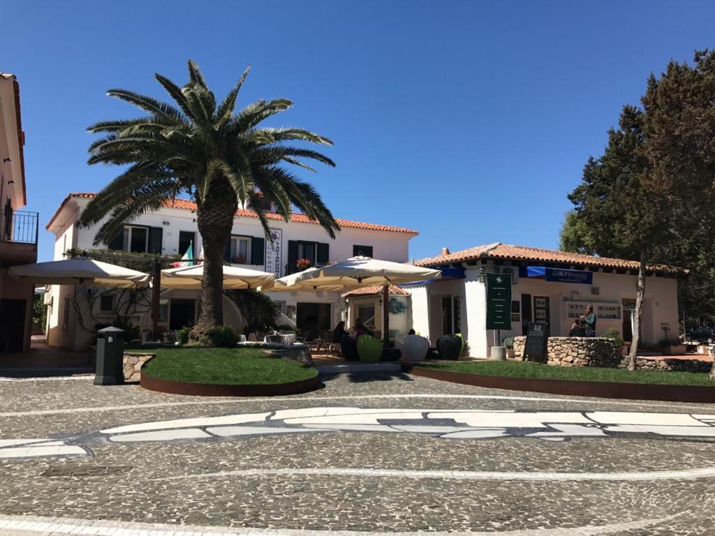 ポルト・ロトンドにあるLocanda Tartarughino - Luxury Suites in Porto Rotondoの椰子の木と傘のある建物