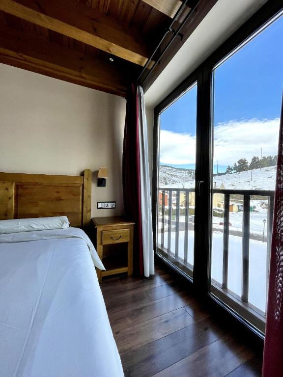 Un dormitorio con una cama y grandes ventanales. en Apartaments Gran Vall, en La Molina