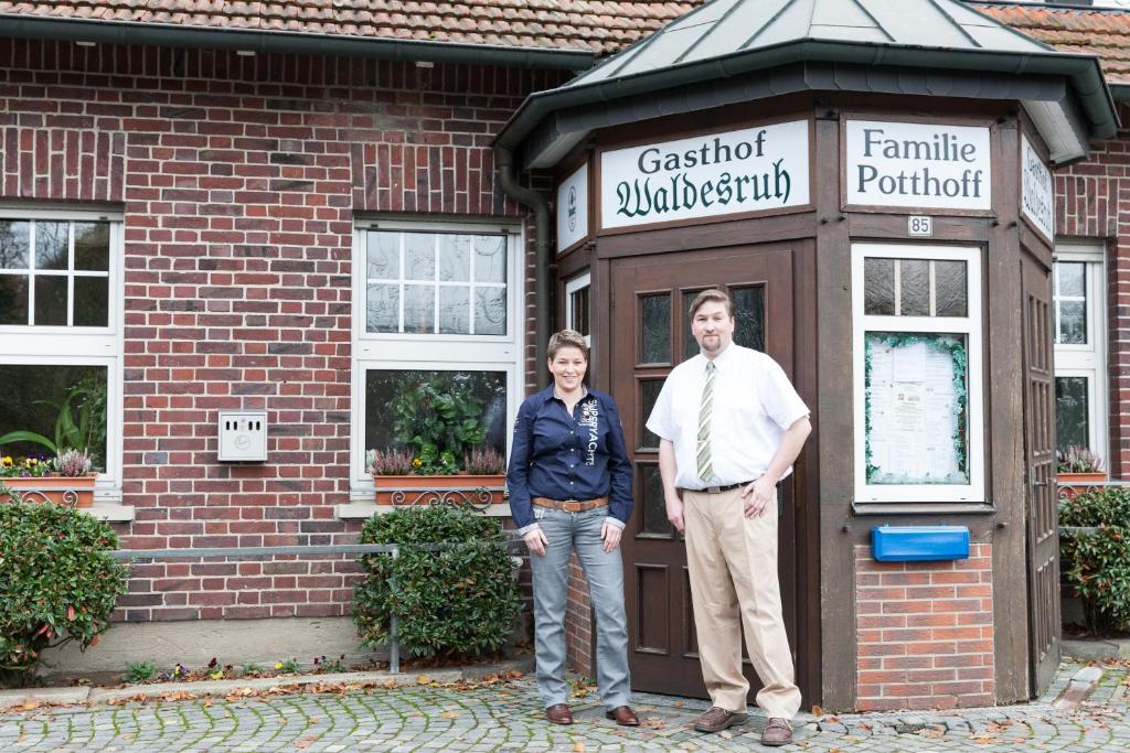 een man en vrouw die voor een gebouw staan bij Gasthof Waldesruh in Saerbeck