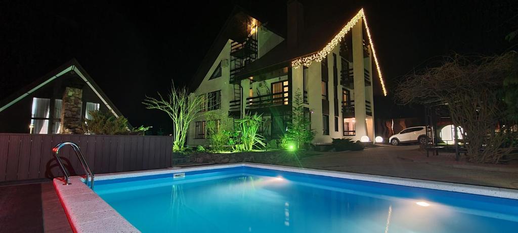 a swimming pool in front of a house at night at Неотель in Krasnaya Polyana