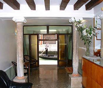 un couloir avec des colonnes et une personne se déplaçant dans un bâtiment dans l'établissement Hotel Caneva, à Venise