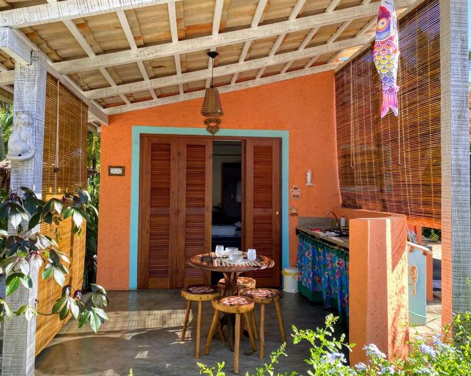 eine Terrasse mit einem Tisch und Stühlen sowie eine Küche in der Unterkunft CasAmar no Condomínio Beira Mar Sargi, Serra Grande in Serra Grande