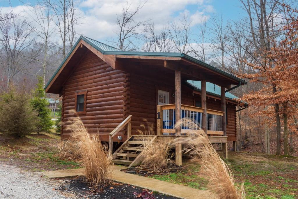 eine Blockhütte im Wald mit einer Veranda in der Unterkunft Pine Creek HC Hocking Hills Cabins in South Bloomingville