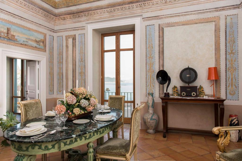 una sala da pranzo con tavolo e fiori di Palazzo Suriano Heritage Hotel a Vietri