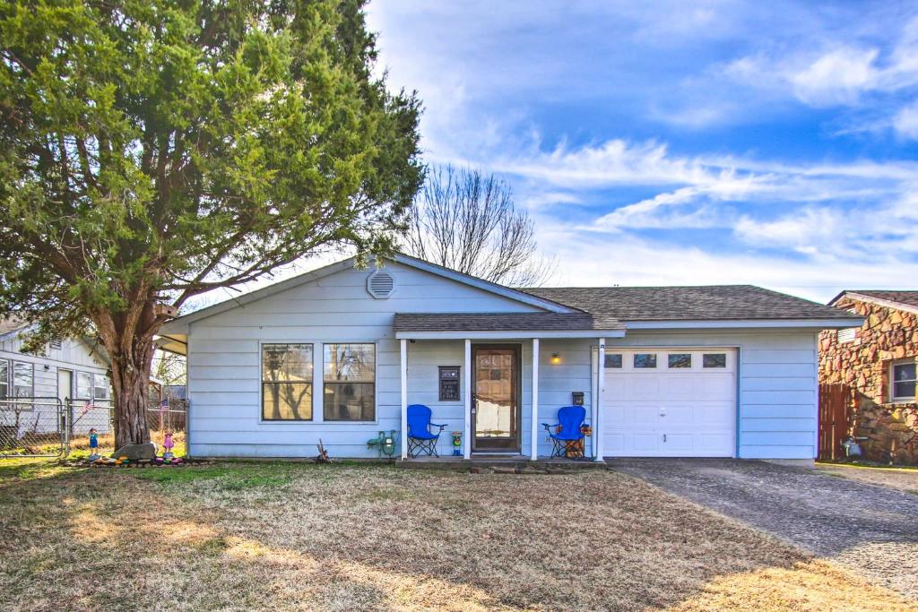 a white house with two blue chairs in front of it at Dog-Friendly Bartlesville Retreat with Yard! in Bartlesville