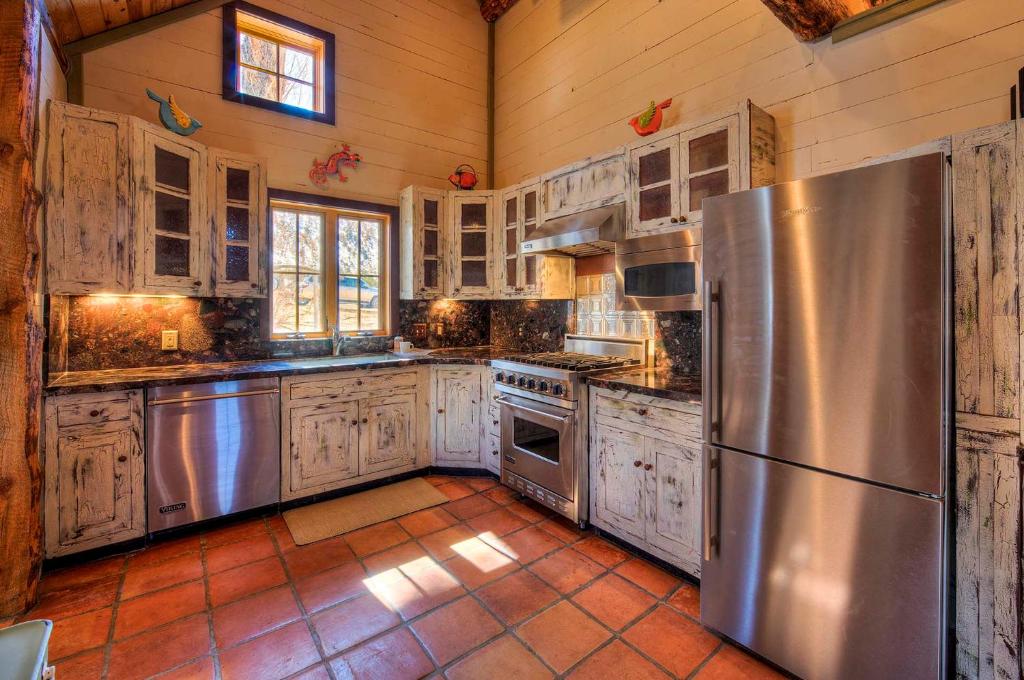 a kitchen with white cabinets and a stainless steel refrigerator at Luxury Log Cabin Less Than 15 Mi to Downtown Moab! in Moab