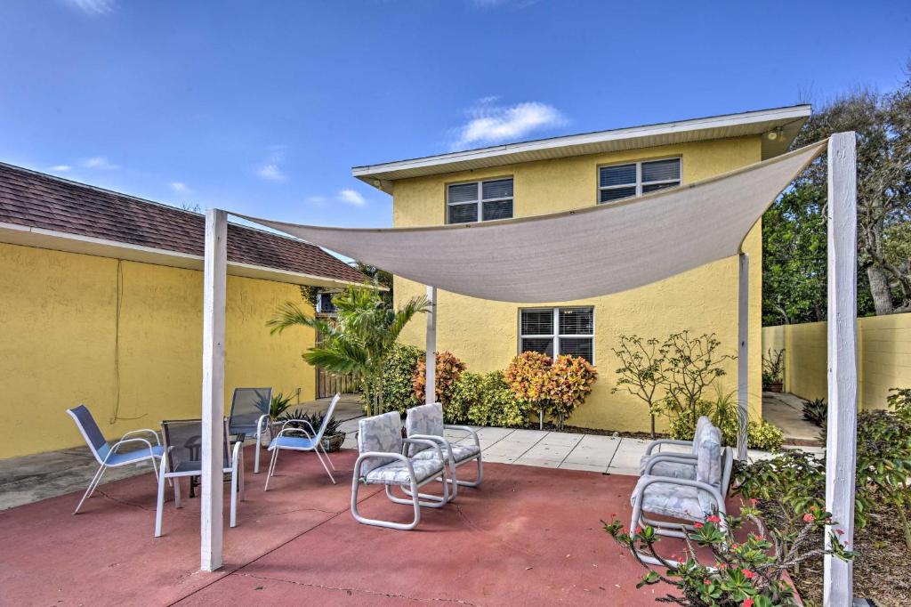 a patio with a table and chairs in front of a yellow house at Sunshine State Escape with Bikes, Walk to Beach in Cocoa Beach