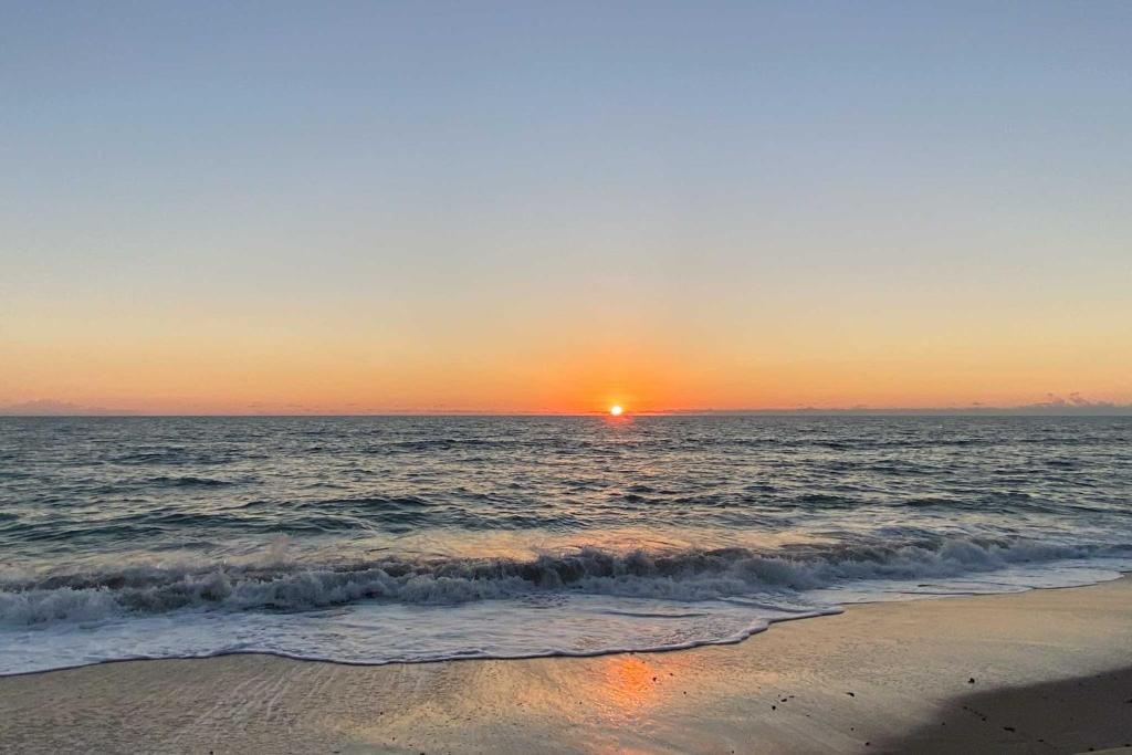 a sunset on the beach with the ocean at Direct Beach Access and View Satellite Beach Condo! in Satellite Beach