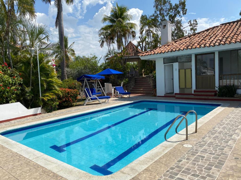a swimming pool with blue chairs and a house at Casa El Peñon in Girardot