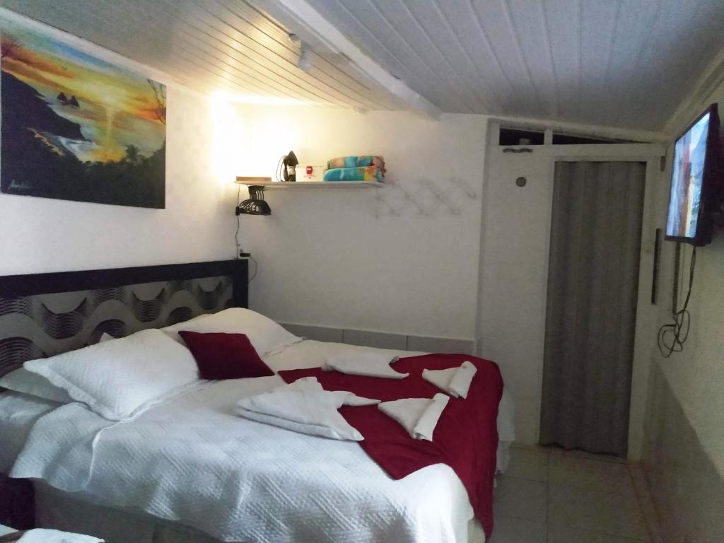 1 dormitorio con 1 cama con manta roja y blanca en Residência da Cláudia, en Fernando de Noronha