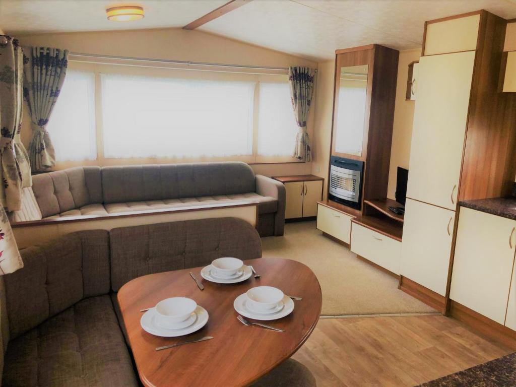 uma sala de estar com uma mesa e um sofá em Cypress Superior Holiday Home em Ingoldmells