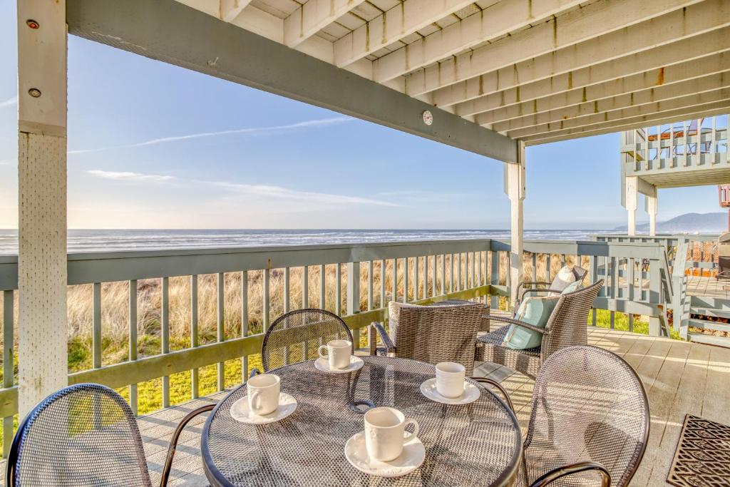a table and chairs on a balcony with a view of the beach at Whale Watcher Condo 1 - Meredith Lodging in Rockaway Beach