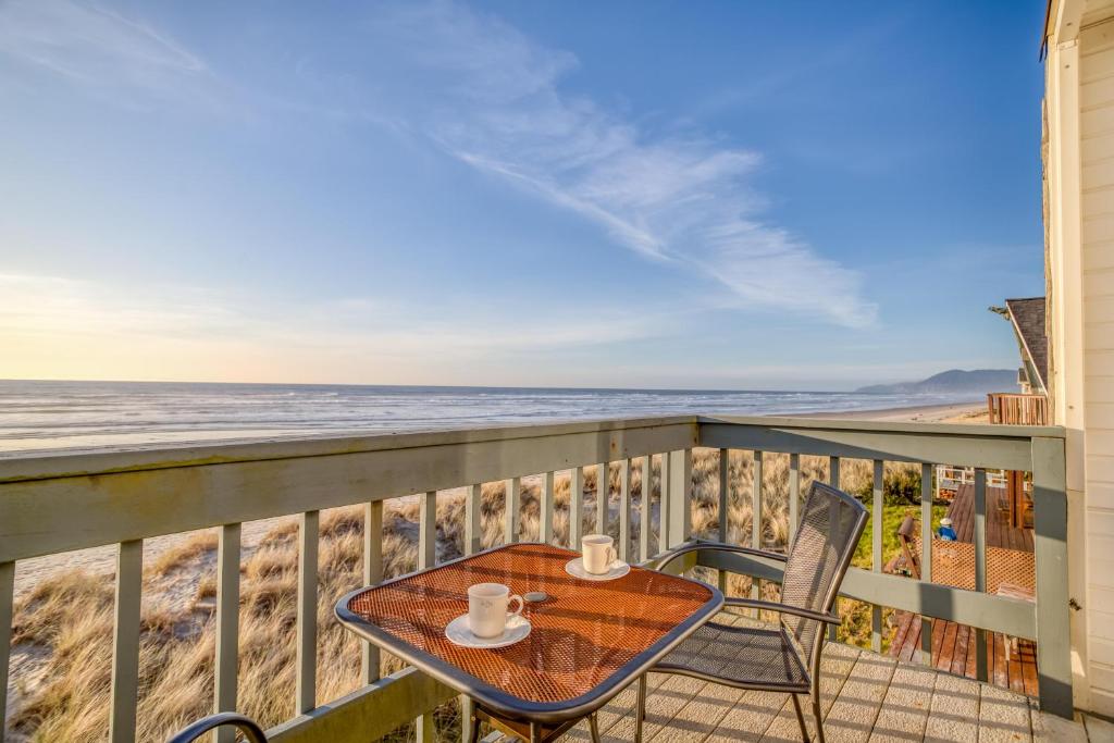 a table and chairs on a balcony with the beach at Whale Watcher Condo #3 in Rockaway Beach