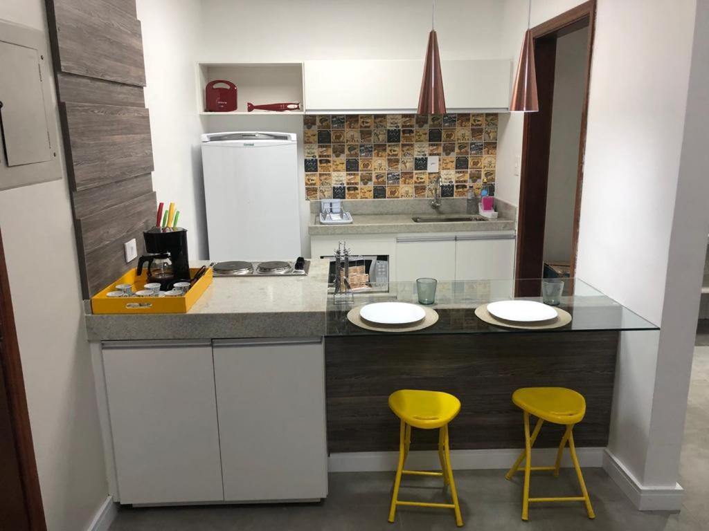 a kitchen with two yellow stools at a counter at Flat Sao Vicente in São Vicente