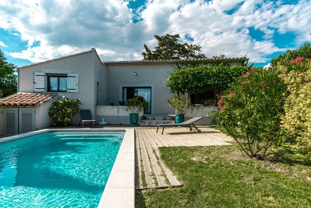 a villa with a swimming pool in front of a house at La Verdière - Contemporary house with garden and private pool in LʼIsle-sur-la-Sorgue