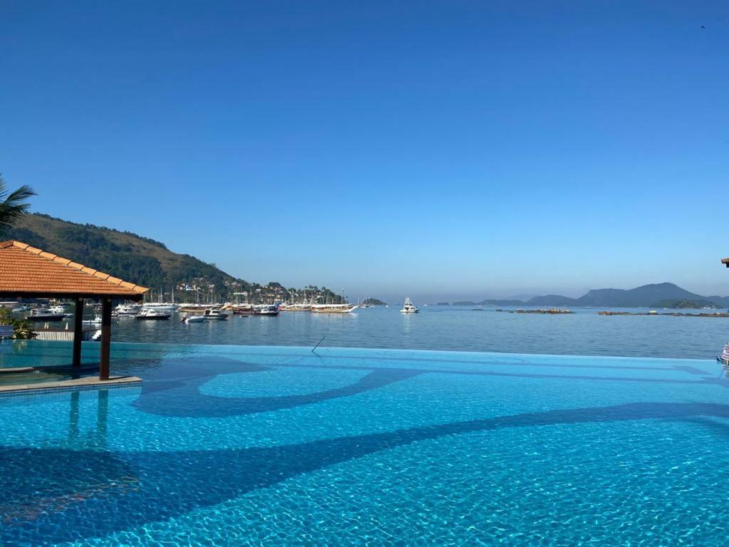 a swimming pool with a view of a body of water at Angra dos Reis Apartamento com Vista para o Mar 6 Condom&iacute;nio Porto Bali Complexo Mercure in Angra dos Reis