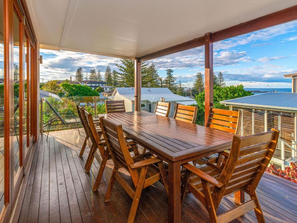 a wooden dining table and chairs on a deck at Seagrass House in Yamba