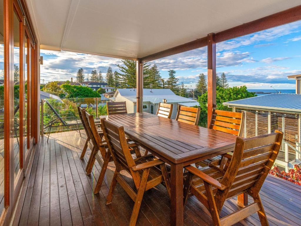 einen Esstisch aus Holz und Stühle auf einer Terrasse in der Unterkunft Seagrass House in Yamba