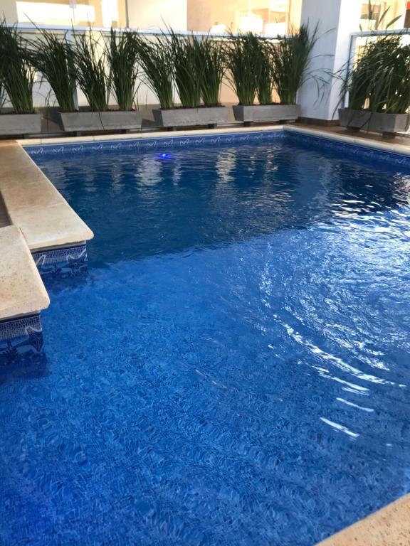 una piscina de agua azul en un edificio en Apartamento C&K FLATBotanics OLIMPIA II, en Olímpia