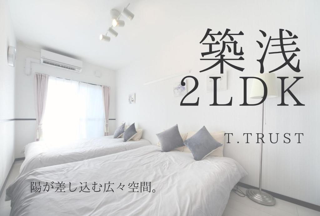 2 Betten in einem weißen Zimmer mit einem Schreibtisch in der Unterkunft EX Itoman Apartment 501 in Itoman