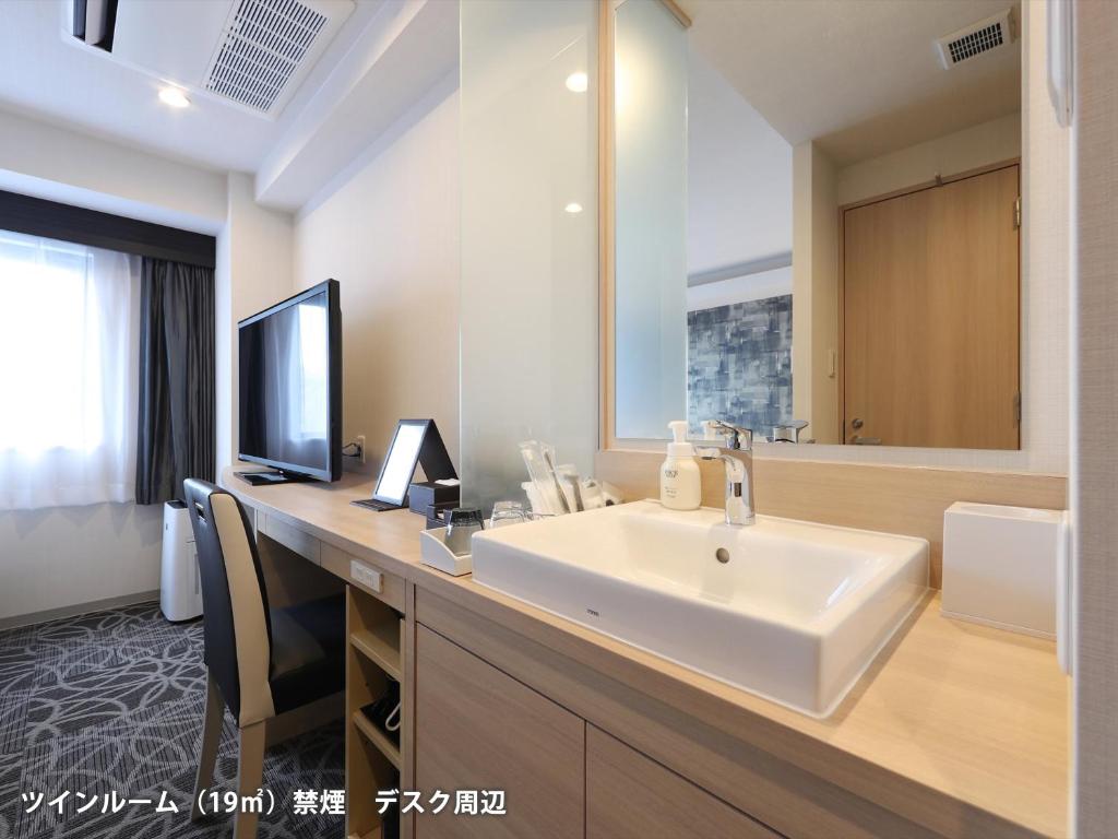 a bathroom with a sink and a large mirror at Hotel Actel Nagoya Nishiki in Nagoya
