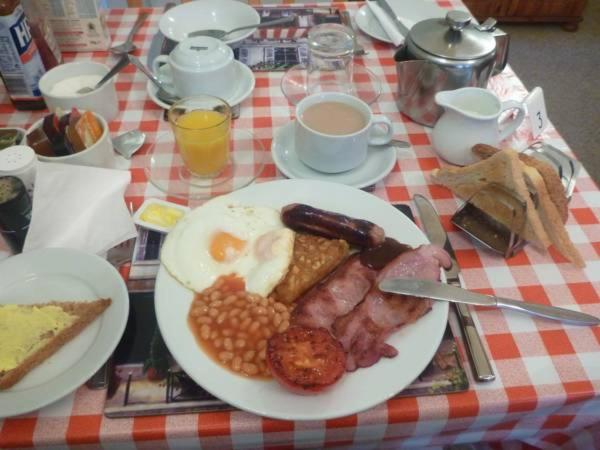a table with a plate of breakfast food with eggs and beans at Lea Hurst B & B in Bournemouth