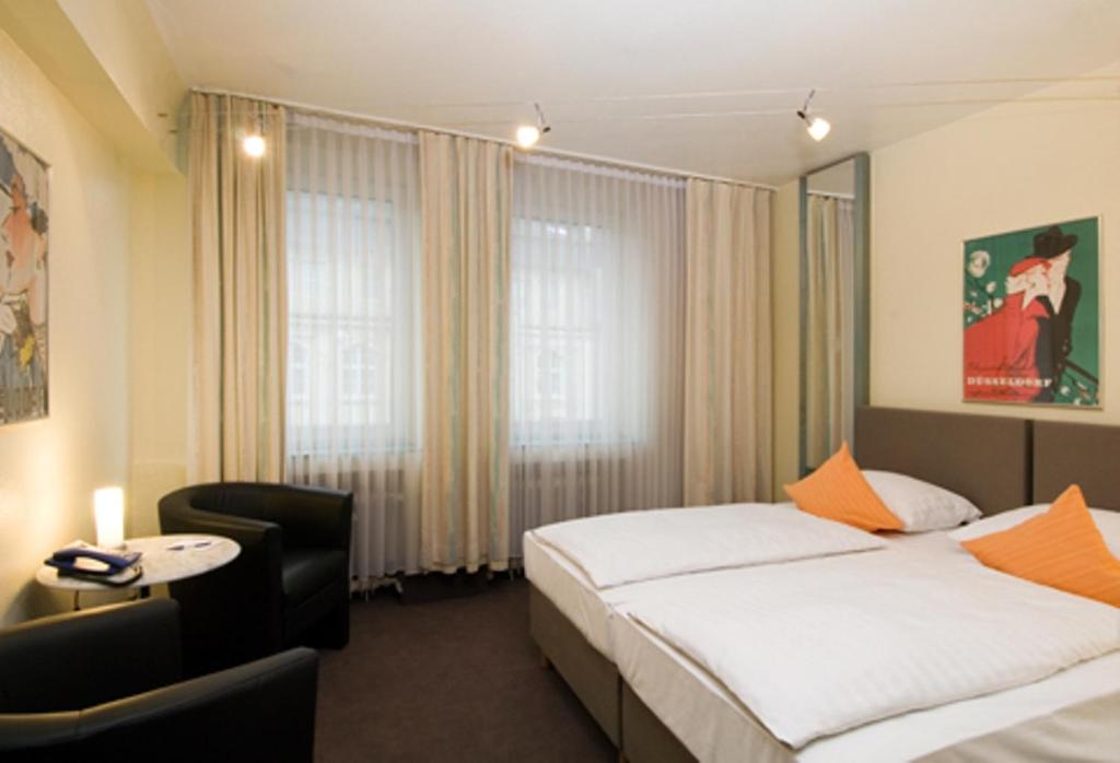 デュッセルドルフにあるHotel Monopol City Centreのベッドと椅子付きのホテルルーム