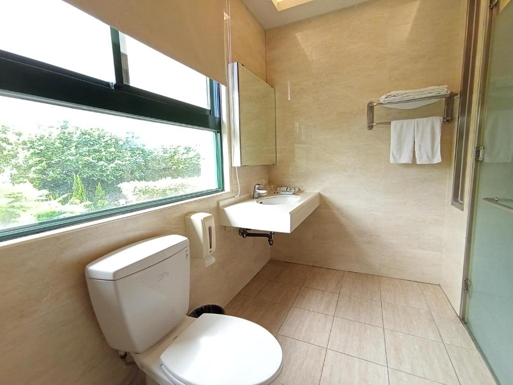 a bathroom with a toilet and a sink and a window at Jin Yong Quan Spa Hotspring Resort in Wanli District