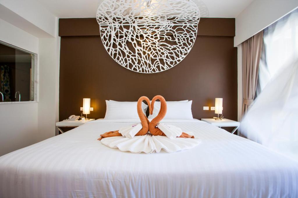 a bedroom with a bed with two towels on it at Coral Inn in Karon Beach
