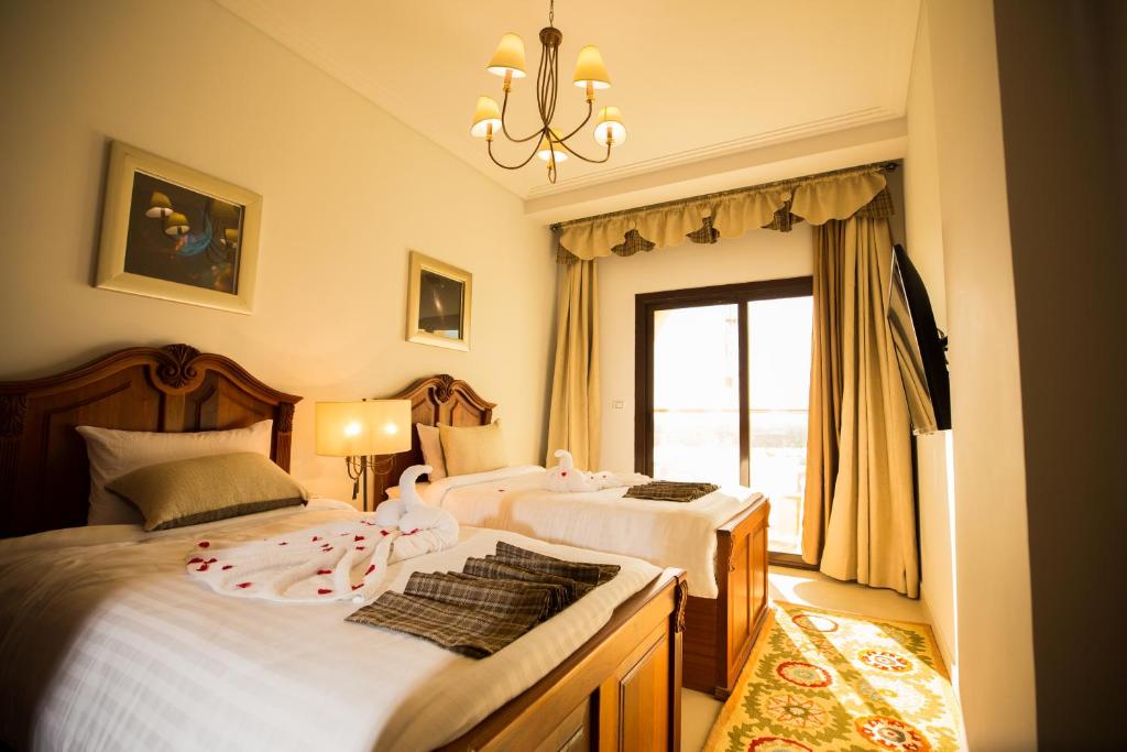 a bedroom with two beds and a chandelier at Holy Family Hotel in Jabal aţ Ţayr
