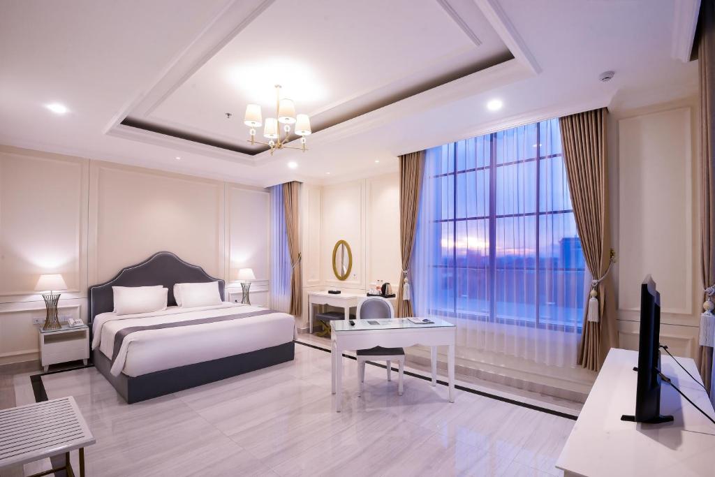 a bedroom with a bed and a large window at Grand Senyum Hotel, Tugu Yogyakarta in Yogyakarta