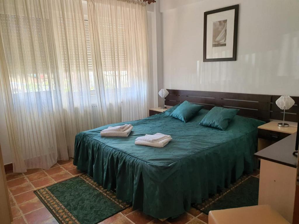 ein Schlafzimmer mit einem grünen Bett und Handtüchern darauf in der Unterkunft Club Cristal Apartments in Neptun