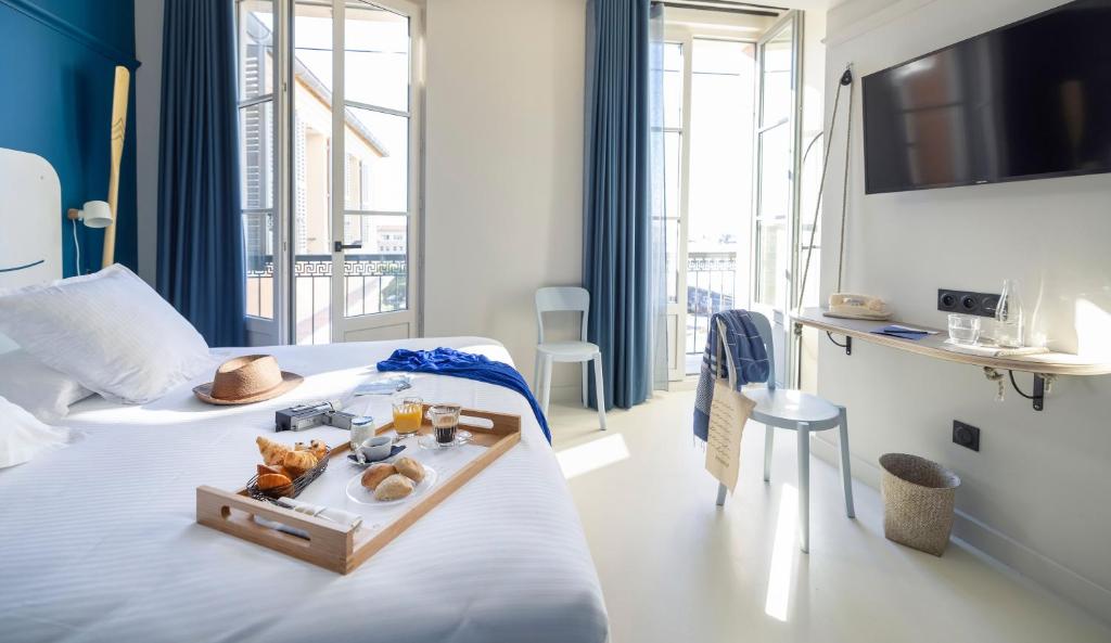a hotel room with a bed with a tray of food on it at L'Eautel Toulon Centre Port in Toulon