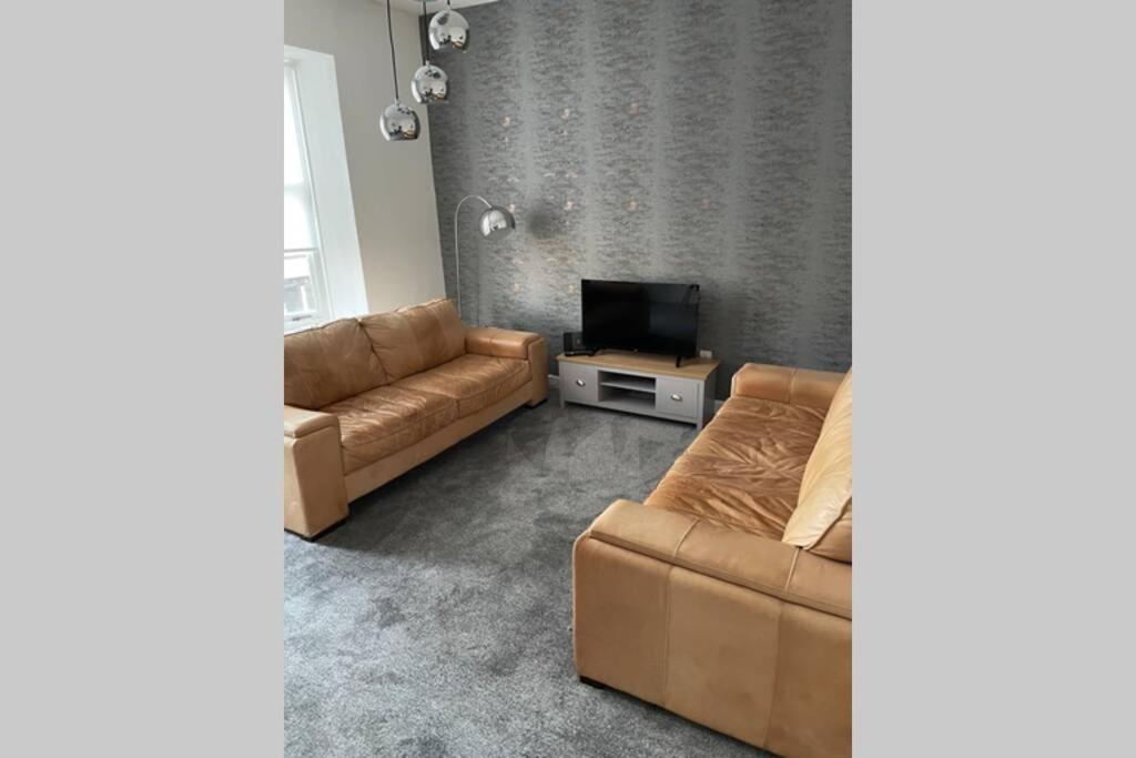 a living room with a couch and a tv at Bellshill central apartments in Bellshill