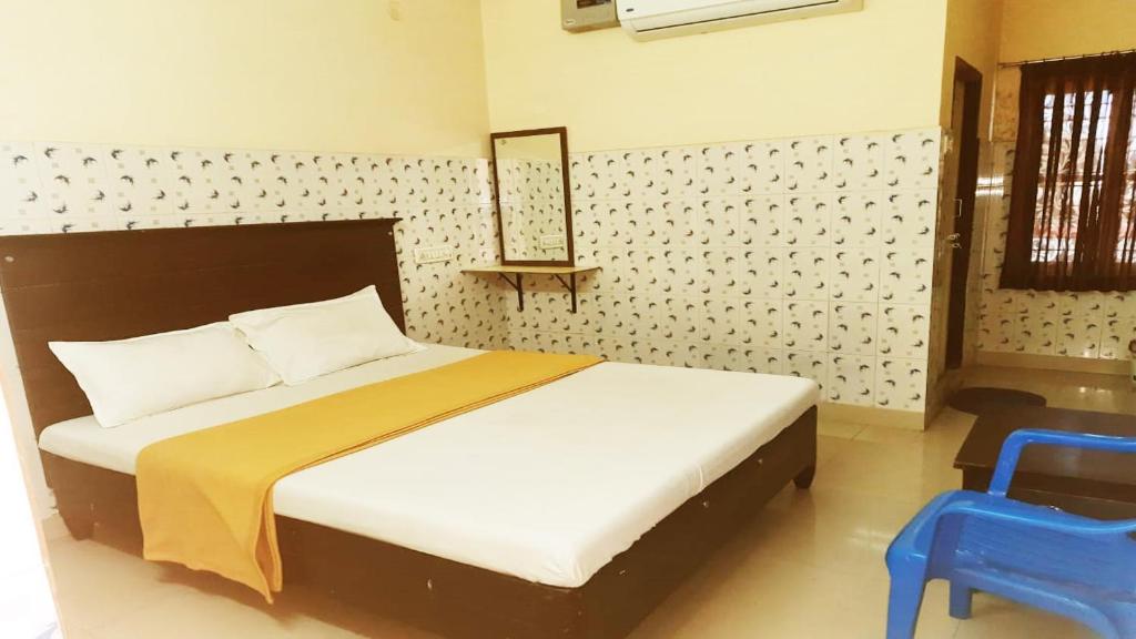 a bedroom with a bed and a blue chair at Vishnu Residency Warangal in Warangal