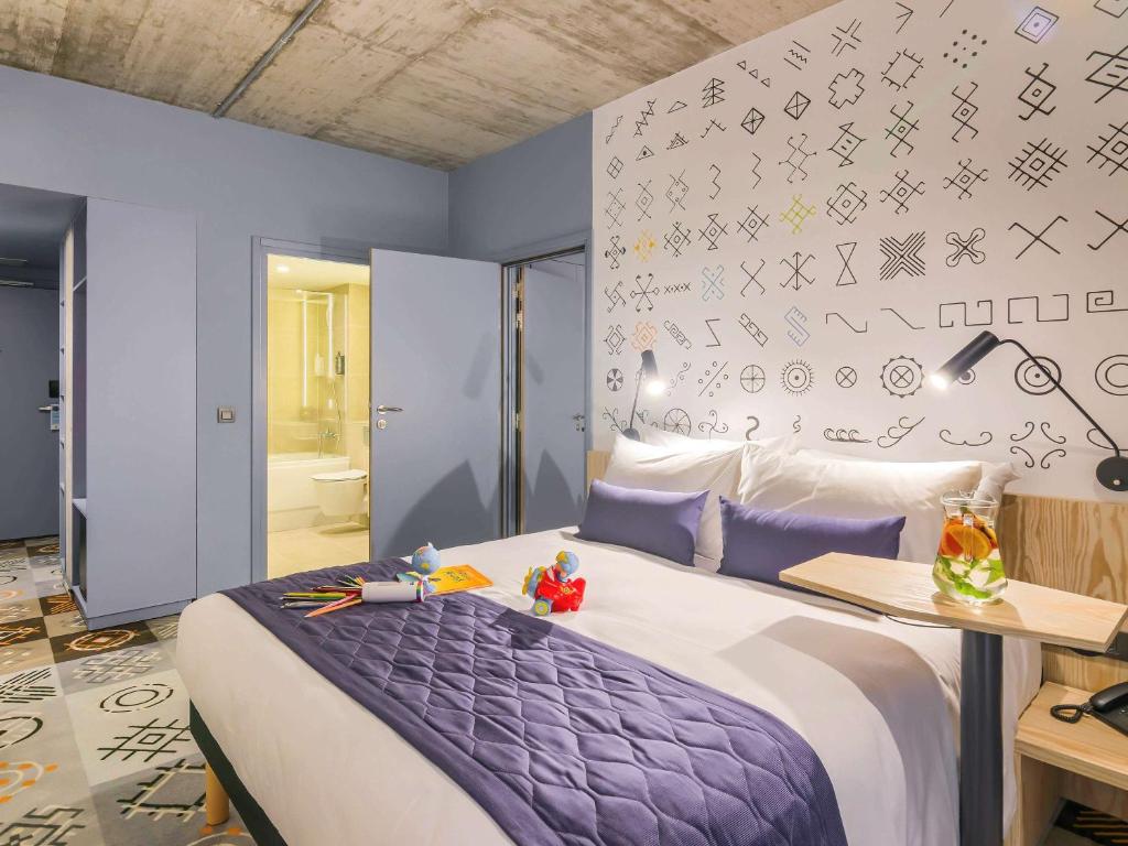 - une chambre avec un lit et une couette violette dans l'établissement ibis Styles Bucharest City Center, à Bucarest