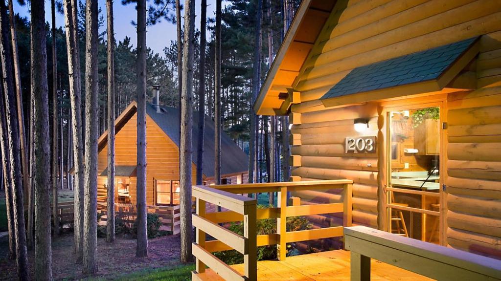 Bluegreen Vacations Christmas Mountain Village, an Ascend Resort في ويسكونسن ديلز: كوخ في الغابة مع شرفة ومنزل