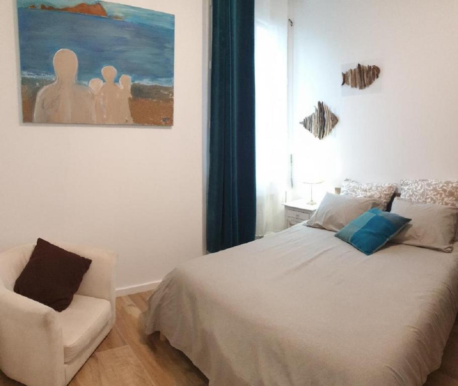 een slaapkamer met een bed en een stoel en een schilderij bij "AuSoleil" 2 pieces cosy ensoleillé, tout à pied, 50 m du vieux port in Saint-Raphaël