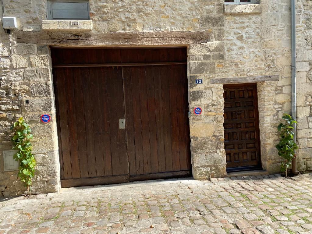 twee houten garagedeuren in een stenen gebouw bij Le Gîte in Senlis