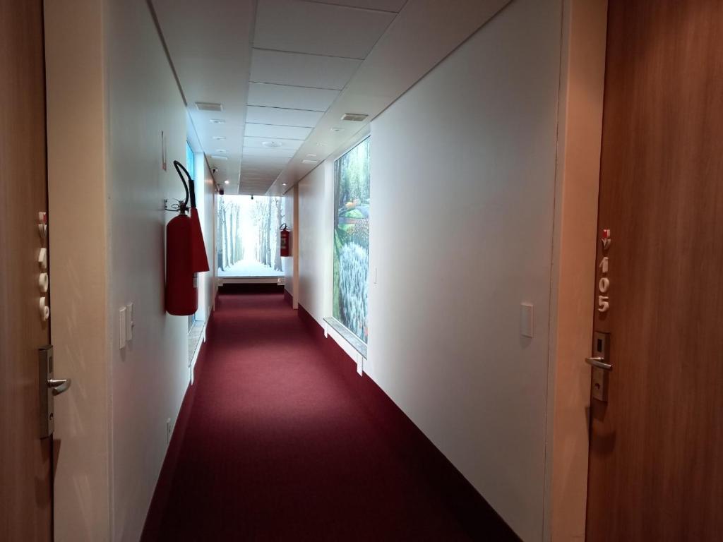 un largo pasillo con una alfombra roja en un edificio en Apartamento em Holambra en Holambra