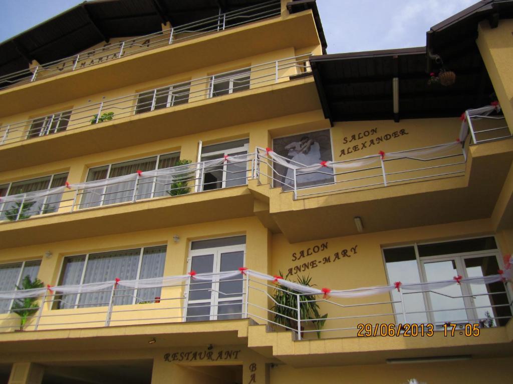 a yellow building with balconies and signs on it at Pensiune Venetia Mariaj in Mioveni