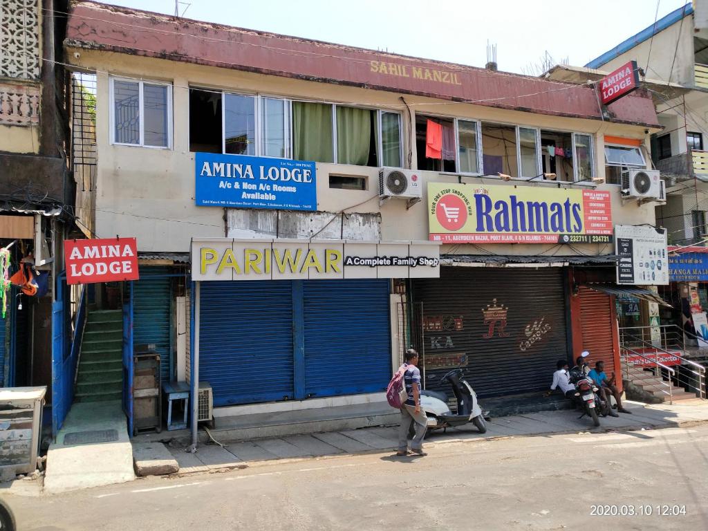 a woman walking down a street in front of a building at AMINA LODGE in Port Blair