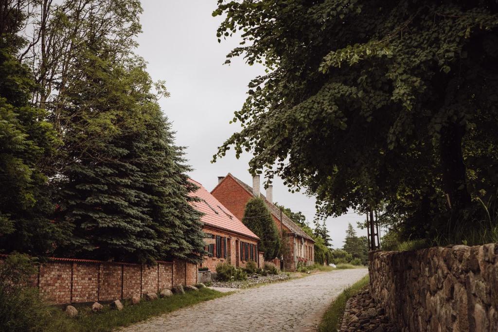 eine Kopfsteinpflasterstraße in einem Dorf mit Häusern und Bäumen in der Unterkunft Osada pod Lipą in Ostrowice
