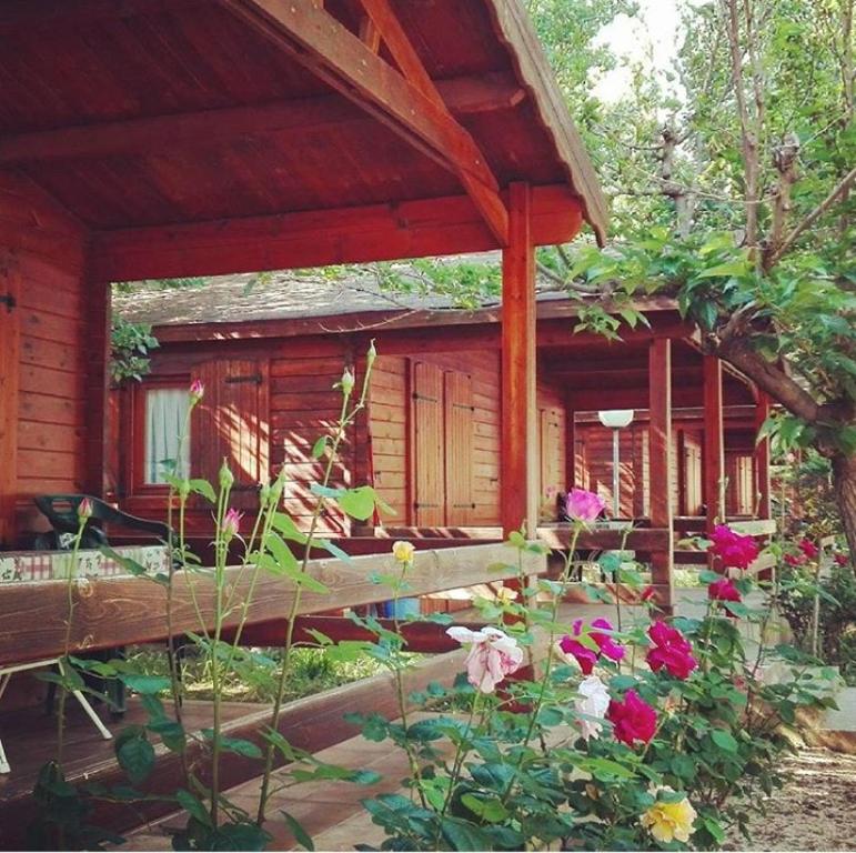 una casa con un banco y flores delante de ella en Bungalow & Camping Fuente De Regrustan en Graus