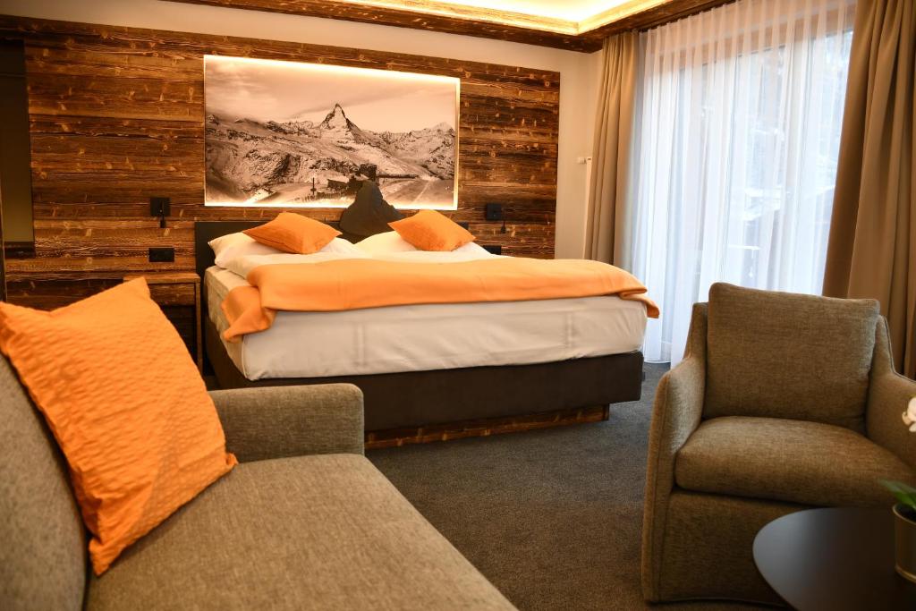 a bedroom with a bed, chair and a lamp at Elite in Zermatt