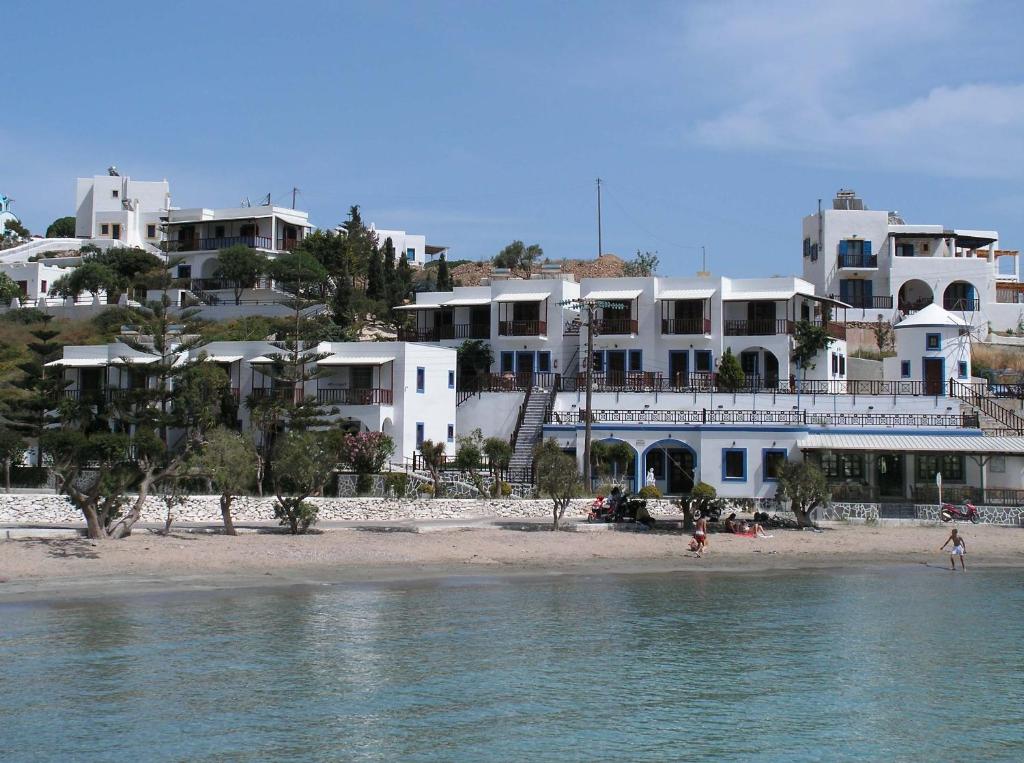 un grupo de edificios blancos en una playa junto al agua en Aphroditi Hotel, en Lipsi