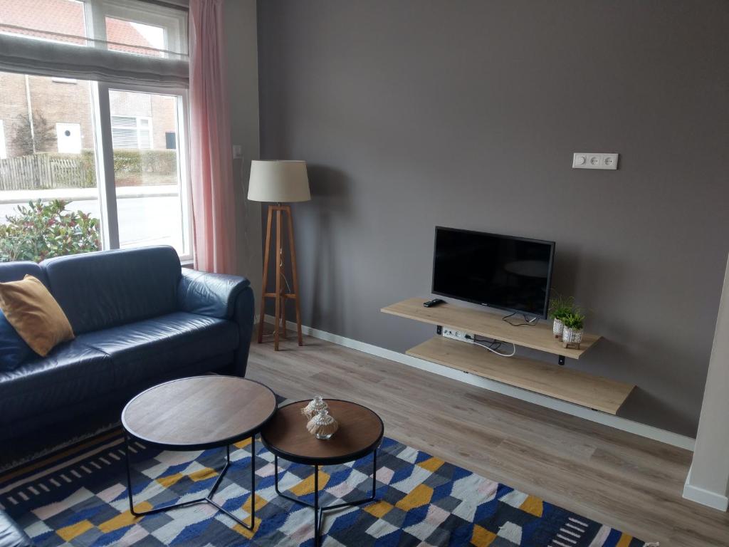 sala de estar con sofá y TV en Volledig Gerenoveerd - Huis aan het strand -Nieuwstraat 4, en Zoutelande