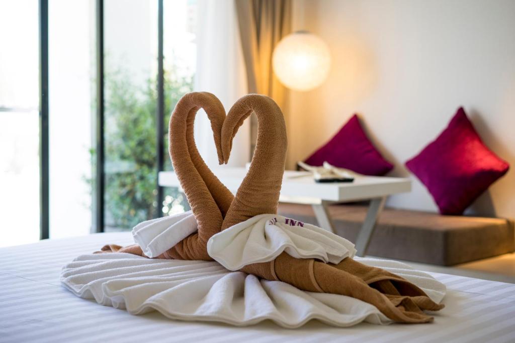 two towel swans sitting on a bed in a hotel room at Coral Inn in Karon Beach